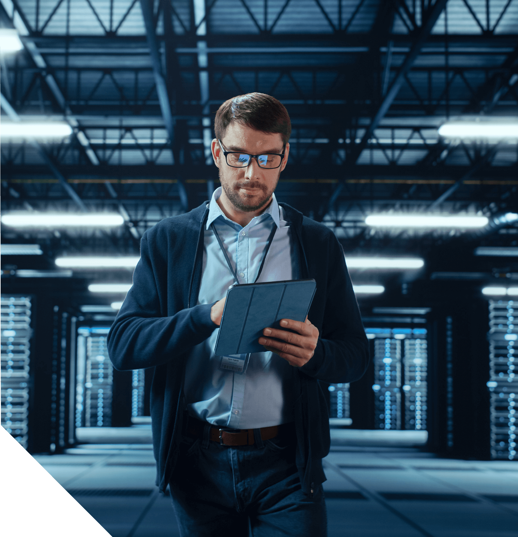 A man in glasses reviews a tablet in a large server room with rows of illuminated equipment.