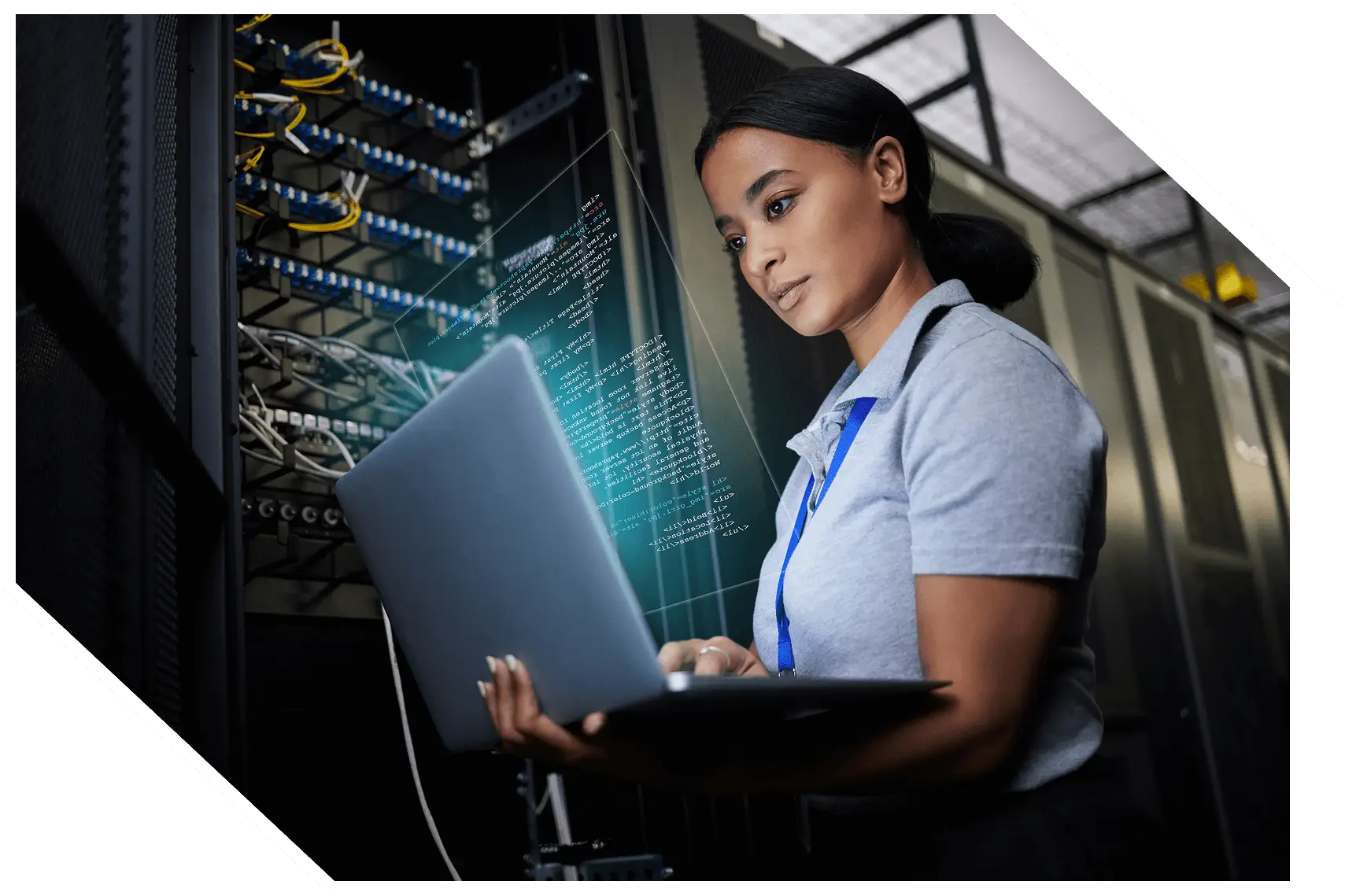 A person stands in a data center working on a laptop, with server racks nearby and digital code visibly projected in the air.
