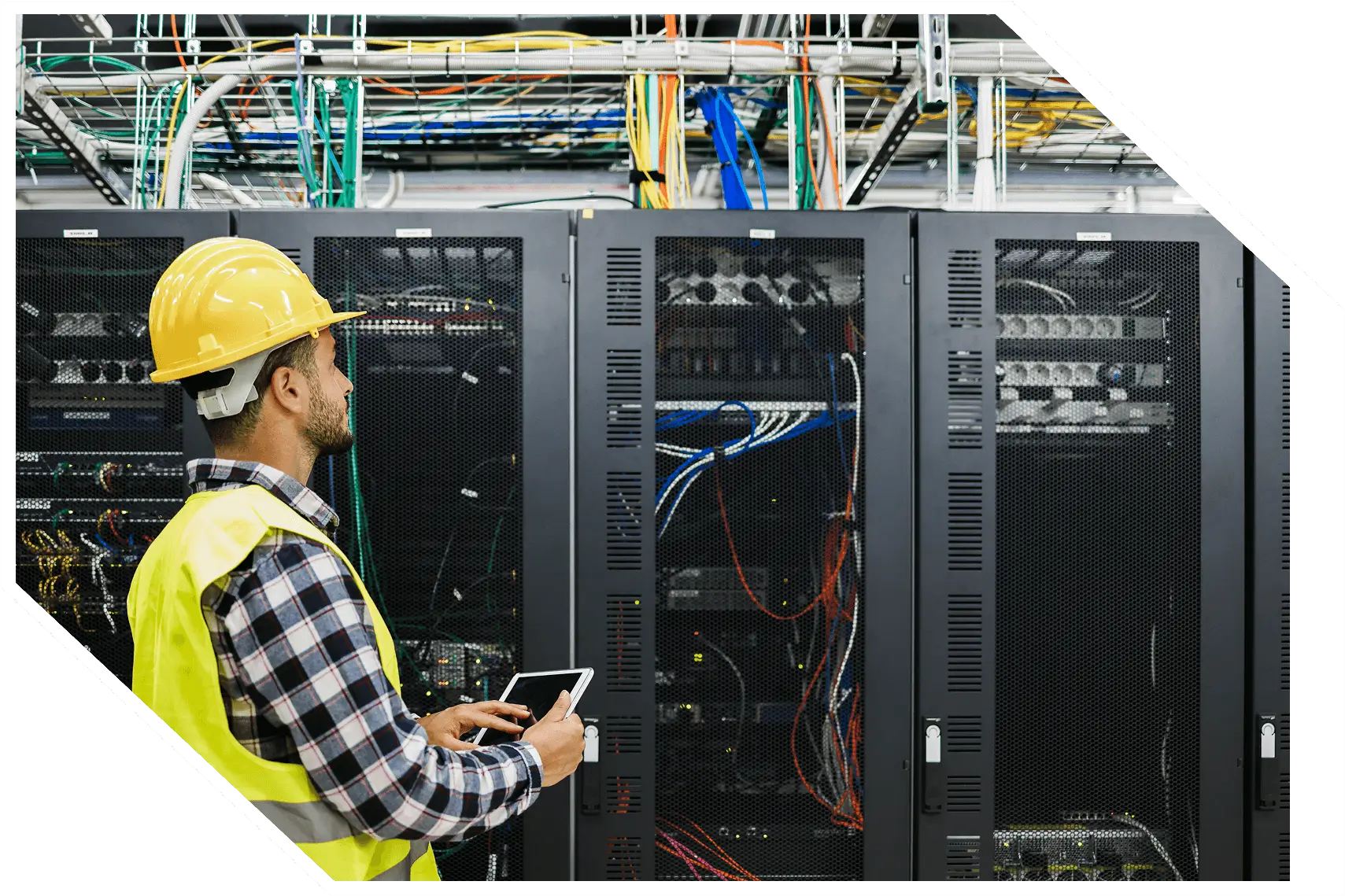 Worker inspecting server racks with tablet.